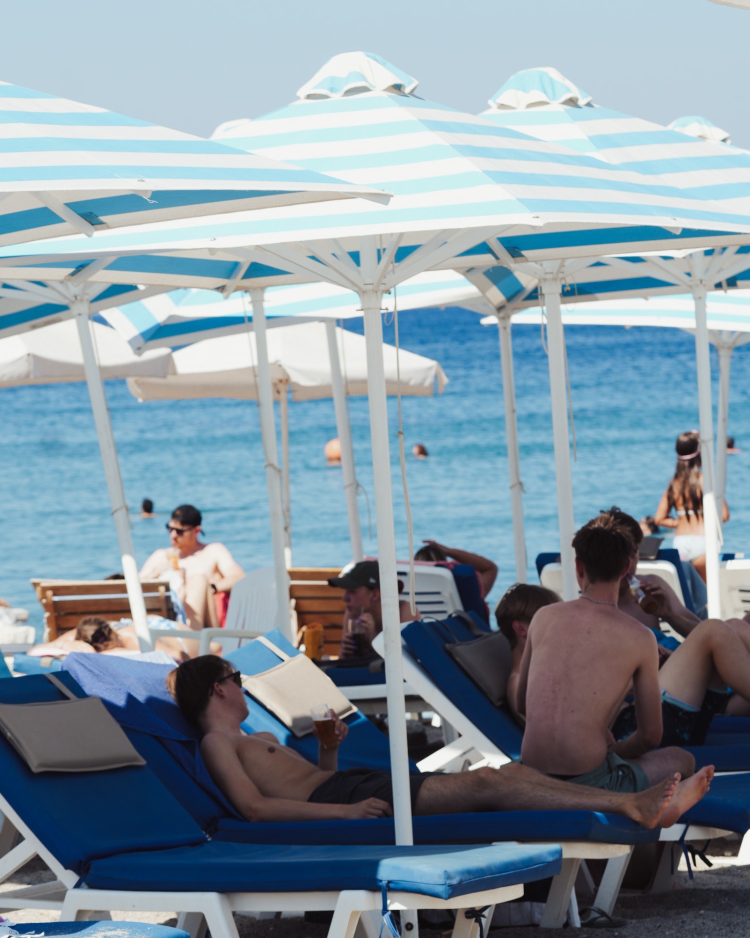Beach loungers with striped umbrellas by the sea
